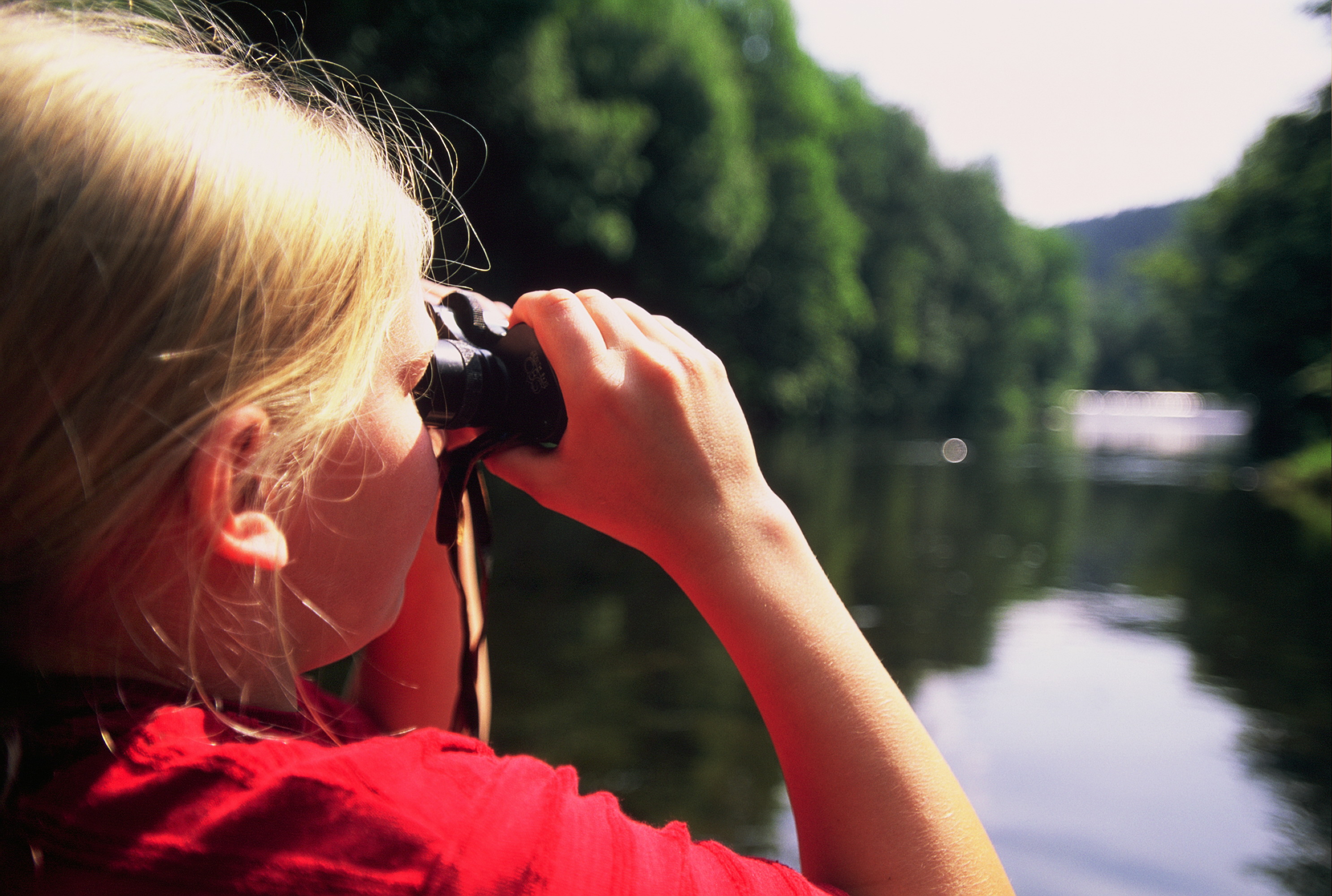 Banner3 Junges Mädchen schaut durch ein Fernglas auf einen See